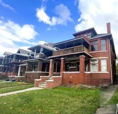 2471-2473 Lothrop St, Detroit, MI 48206 - view of front of home featuring brick siding, a front yard, a chimney, and a balcony