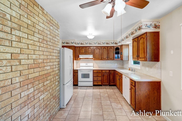 1460 N Peterson Rd, Muskegon, MI 49445 - kitchen featuring white appliances, under cabinet range hood, brick wall, brown cabinets, and light countertops
