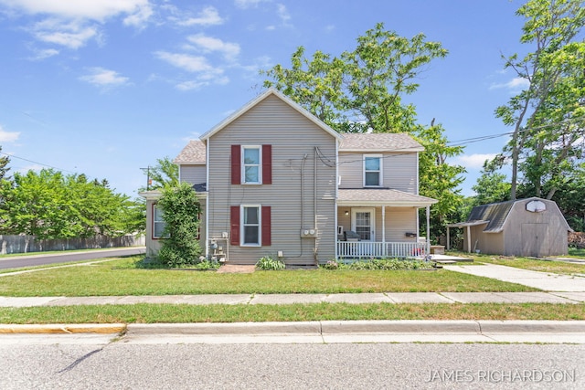 1002 Madison St, Grand Haven, MI 49417 - traditional-style home with covered porch, a storage unit, and a shingled roof