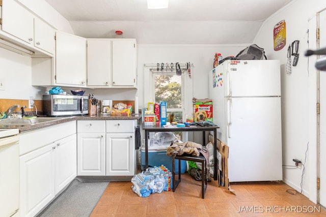 1002 Madison St, Grand Haven, MI 49417 - kitchen with freestanding refrigerator, stainless steel microwave, vaulted ceiling, and white cabinets