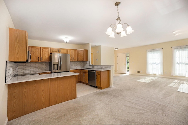 5724 Hampshire Ln, Ypsilanti, MI 48197 - kitchen with a peninsula, stainless steel appliances, brown cabinets, a chandelier, and light countertops
