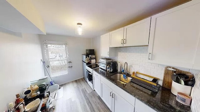 101 E Mckay St, Saline, MI 48176 - kitchen featuring dark stone counters, white cabinets, decorative backsplash, light wood-style flooring, and oven