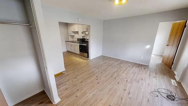 101 E Mckay St, Saline, MI 48176 - kitchen with stainless steel range with electric stovetop, light wood finished floors, white cabinetry, and under cabinet range hood