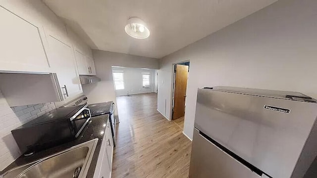 101 E Mckay St, Saline, MI 48176 - kitchen featuring fridge, white cabinetry, light wood finished floors, under cabinet range hood, and tasteful backsplash