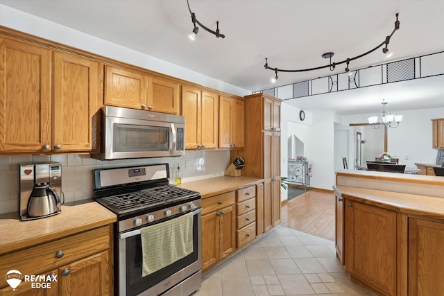 416 State Park Rd, Ortonville, MI 48462 - kitchen with appliances with stainless steel finishes, a chandelier, brown cabinetry, and light countertops