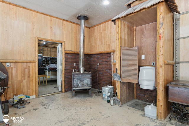 416 State Park Rd, Ortonville, MI 48462 - misc room featuring unfinished concrete flooring, a wood stove, and wooden walls