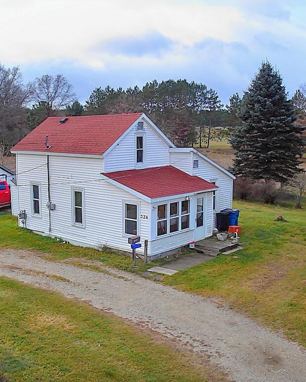 524 S Cherry St, Evart, MI 49631 - back of house featuring a lawn, a shingled roof, and driveway