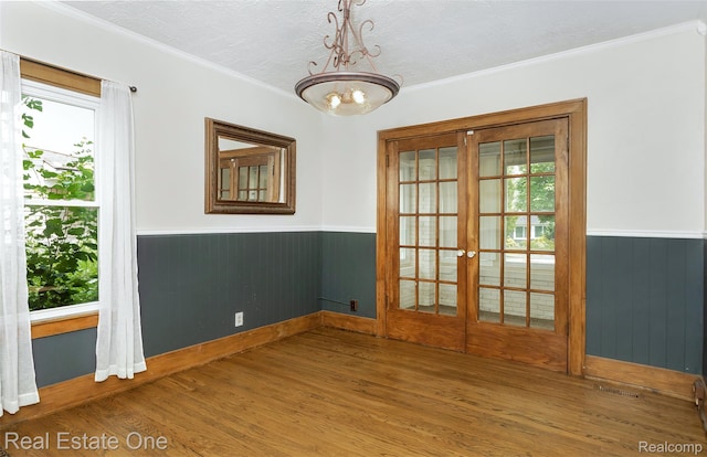 14711 Borgman St, Oak Park, MI 48237 - empty room with french doors, a wainscoted wall, wood finished floors, ornamental molding, and a chandelier