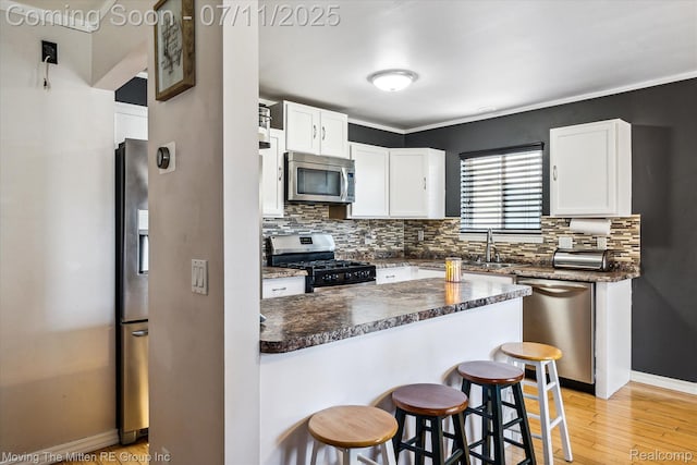 21203 Collingham Ave, Farmington Hills, MI 48336 - kitchen featuring stainless steel appliances, a kitchen breakfast bar, backsplash, and white cabinets