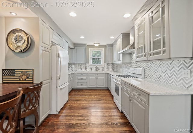 3811 Benstein Rd, Commerce Twp, MI 48382 - kitchen featuring white appliances, wall chimney range hood, dark wood-style flooring, glass insert cabinets, and decorative backsplash