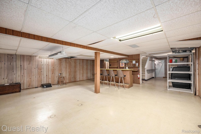 31618 Winchester Ave, Warren, MI 48092 - finished below grade area featuring a paneled ceiling, a dry bar, wooden walls, and tile patterned floors