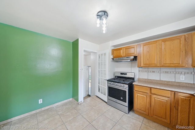 18140 Westover Ave, Southfield, MI 48075 - kitchen featuring stainless steel gas range, under cabinet range hood, light countertops, tasteful backsplash, and light tile patterned floors