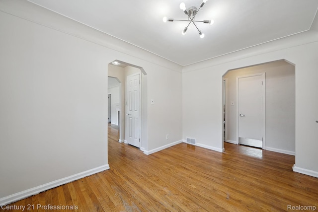 18140 Westover Ave, Southfield, MI 48075 - unfurnished room with arched walkways, a chandelier, and light wood-style flooring