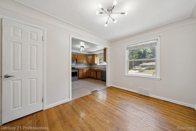 18140 Westover Ave, Southfield, MI 48075 - unfurnished living room with light wood-style flooring and a chandelier