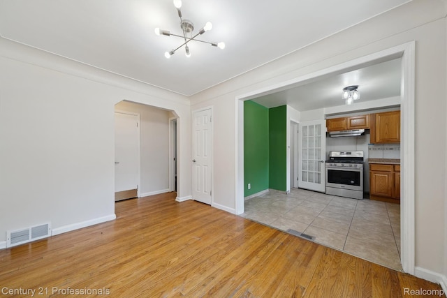 18140 Westover Ave, Southfield, MI 48075 - unfurnished living room featuring a chandelier, arched walkways, and light wood-type flooring