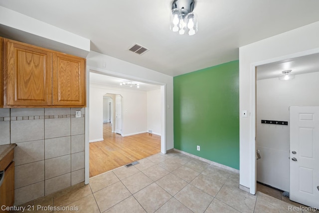18140 Westover Ave, Southfield, MI 48075 - kitchen with light tile patterned floors, arched walkways, a chandelier, and brown cabinets