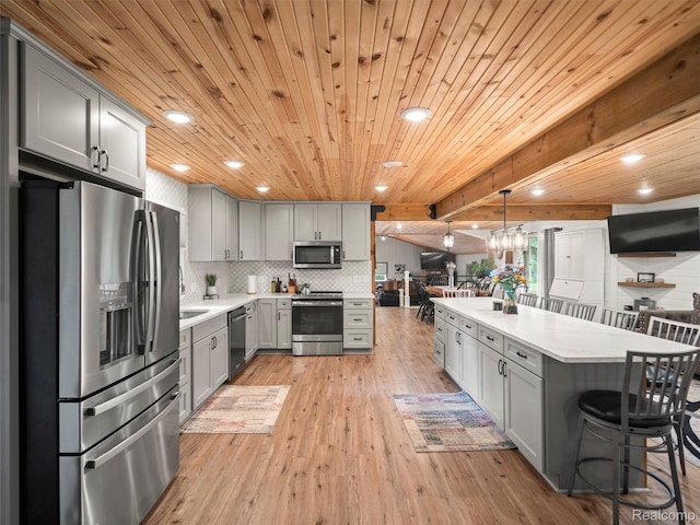 3365 Howland Rd, Almont, MI 48003 - kitchen featuring appliances with stainless steel finishes, gray cabinets, light countertops, light wood-style floors, and a kitchen bar