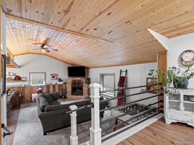 3365 Howland Rd, Almont, MI 48003 - living room featuring lofted ceiling, ceiling fan, wooden walls, wood ceiling, and a stone fireplace