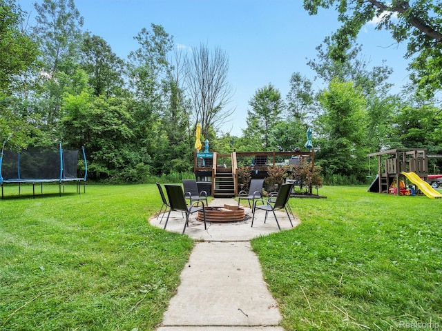 3365 Howland Rd, Almont, MI 48003 - view of grassy yard with a trampoline, an outdoor fire pit, a patio, a deck, and a playground