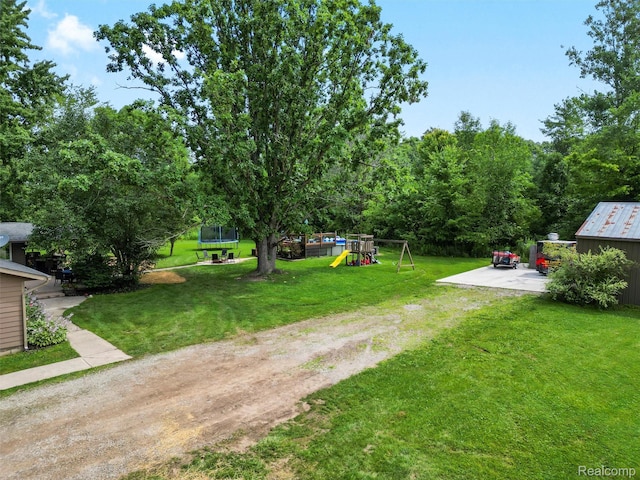 3365 Howland Rd, Almont, MI 48003 - view of green lawn with a trampoline, a playground, and driveway