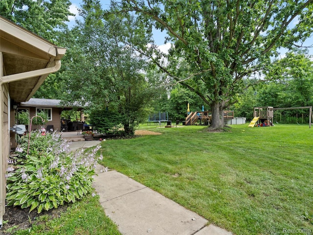 3365 Howland Rd, Almont, MI 48003 - view of green lawn featuring a trampoline, a playground, a patio, and view of wooded area
