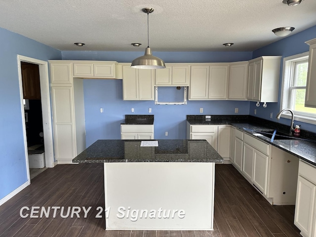 7265 Deweigan Ln, Mount Pleasant, MI 48858 - kitchen featuring dark wood-style floors, dark stone counters, a kitchen island, a textured ceiling, and hanging light fixtures