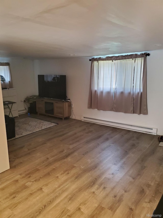 244 S Sherman St, Vassar, MI 48768 - unfurnished living room featuring a baseboard radiator, wood finished floors, and plenty of natural light