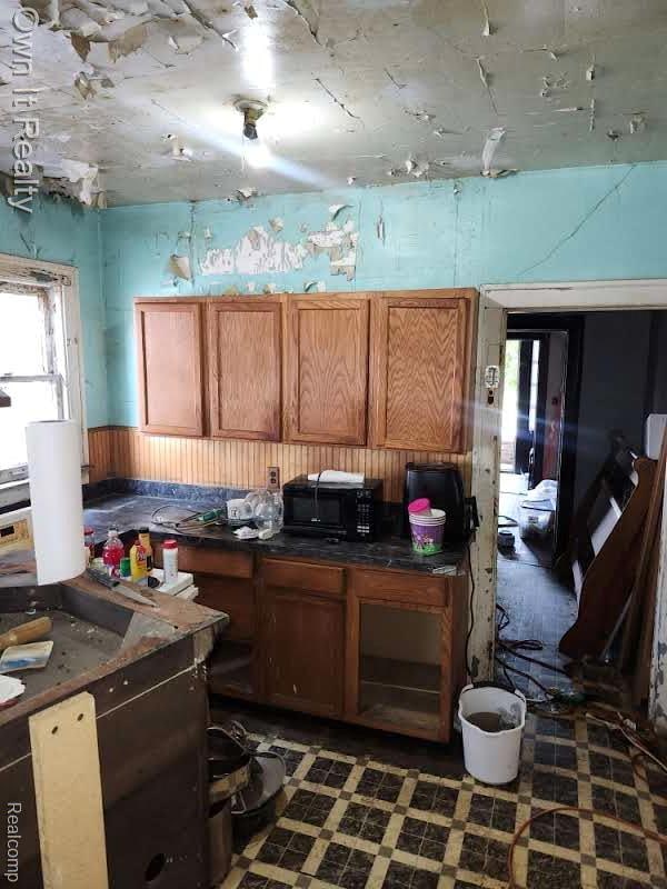 1950 Lawrence St, Detroit, MI 48206 - kitchen with black microwave, brown cabinetry, dark countertops, and tile patterned floors