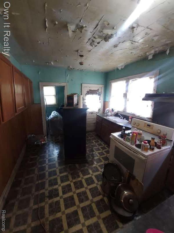 1950 Lawrence St, Detroit, MI 48206 - kitchen with white stove, dark flooring, and brown cabinets