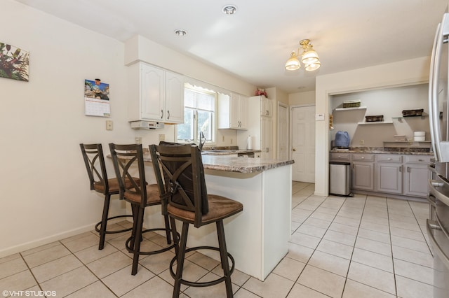 4175 Schmuhl Rd, Coloma, MI 49038 - kitchen with a peninsula, light tile patterned floors, a kitchen breakfast bar, white cabinetry, and light stone countertops