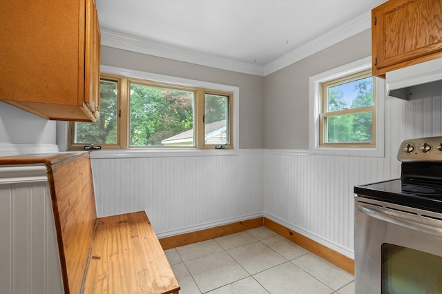 1402 Gracel St, Jackson, MI 49202 - kitchen with electric range, light tile patterned flooring, wainscoting, crown molding, and brown cabinetry