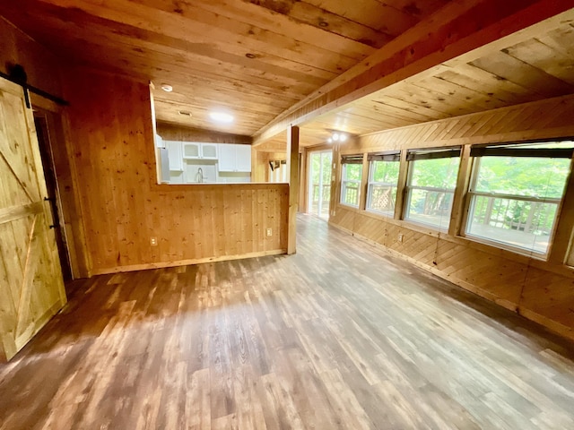 18572 Oxbow Dr, Barryton, MI 49305 - unfurnished living room with wooden walls, a barn door, wood finished floors, wooden ceiling, and lofted ceiling