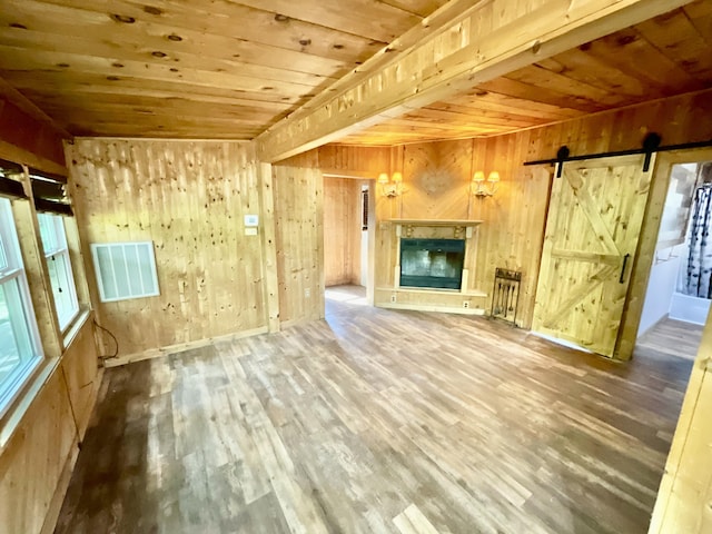 18572 Oxbow Dr, Barryton, MI 49305 - unfurnished living room with wooden ceiling, wood finished floors, wooden walls, a barn door, and a fireplace