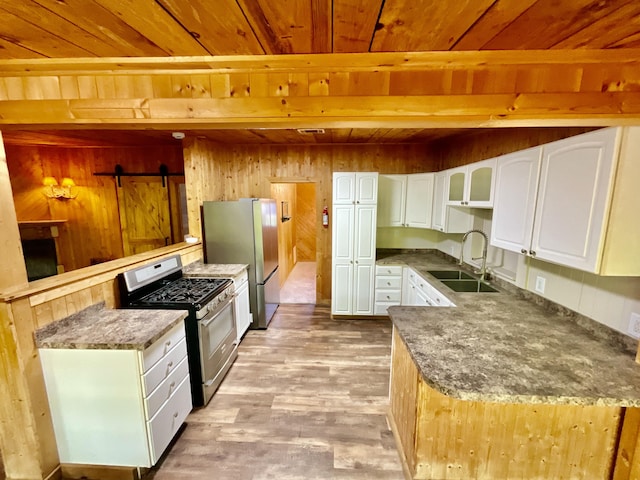 18572 Oxbow Dr, Barryton, MI 49305 - kitchen with stainless steel appliances, a wooden ceiling with exposed beams, light wood-style floors, wood walls, and white cabinets