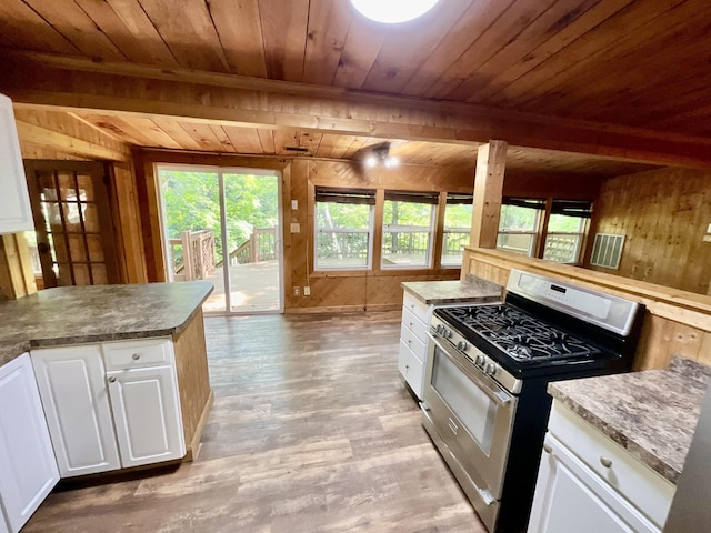 18572 Oxbow Dr, Barryton, MI 49305 - kitchen with stainless steel range with gas stovetop, a wooden ceiling with exposed beams, wood walls, plenty of natural light, and light wood-style floors