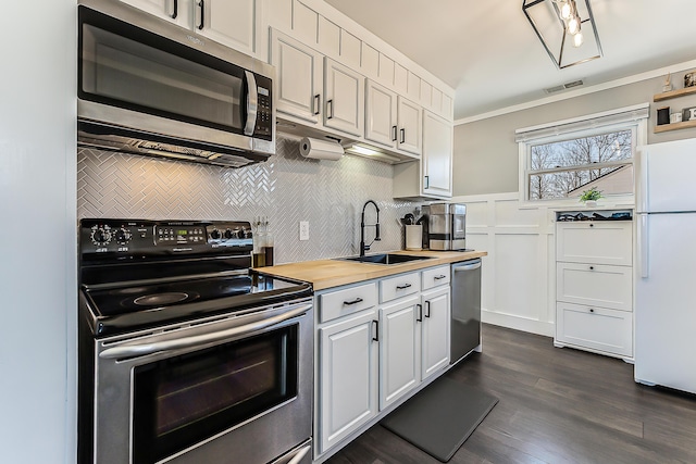 405 Spring St, Saline, MI 48176 - kitchen featuring appliances with stainless steel finishes, decorative backsplash, dark wood-type flooring, white cabinetry, and butcher block countertops