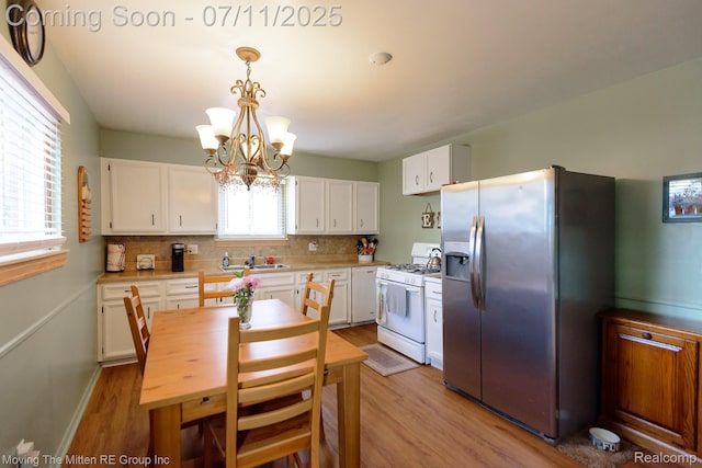 13620 Aston St, Romulus, MI 48174 - kitchen with stainless steel fridge, white gas range oven, light wood finished floors, and white cabinetry