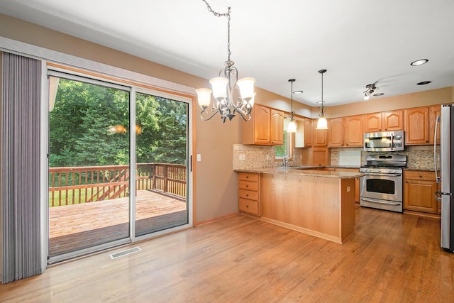 4291 Bramblewood Ct, Dorr, MI 49323 - kitchen with appliances with stainless steel finishes, a peninsula, decorative backsplash, plenty of natural light, and recessed lighting