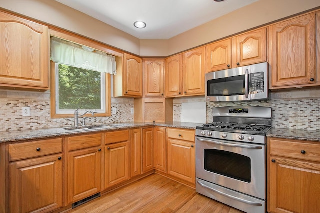 4291 Bramblewood Ct, Dorr, MI 49323 - kitchen featuring stainless steel appliances, stone counters, light wood-style flooring, and decorative backsplash
