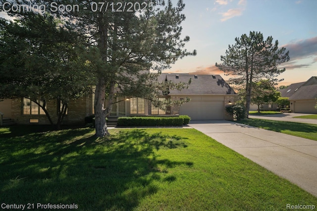 17012 Coral Ln, Macomb, MI 48042 - view of front of home featuring a lawn, a garage, driveway, and brick siding