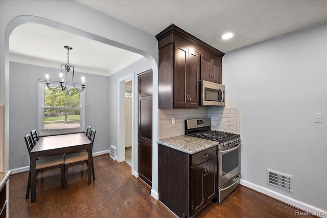 1450 Hampton Rd, Grosse Pointe Woods, MI 48236 - kitchen featuring appliances with stainless steel finishes, arched walkways, a chandelier, dark brown cabinetry, and dark wood-type flooring