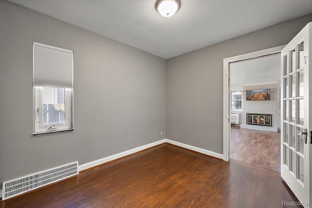 1450 Hampton Rd, Grosse Pointe Woods, MI 48236 - spare room with wood finished floors and a brick fireplace