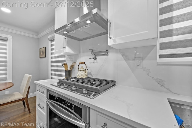 23167 Cromwell St, Canton, MI 48128 - kitchen with stainless steel appliances, wall chimney exhaust hood, white cabinetry, ornamental molding, and wood finished floors