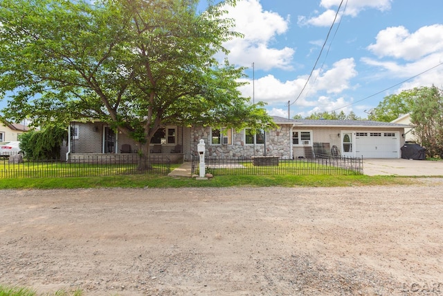 753 Vaniman Island Dr, Brooklyn, MI 49230 - view of front of house with an attached garage, stone siding, concrete driveway, and a fenced front yard