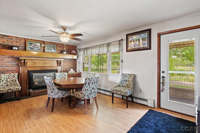 753 Vaniman Island Dr, Brooklyn, MI 49230 - dining room featuring baseboard heating, light wood-type flooring, a glass covered fireplace, ceiling fan, and ornamental molding