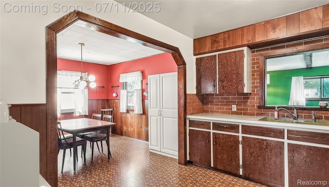 1845 Van Courtland Dr, Troy, MI 48083 - kitchen featuring wainscoting, light countertops, wood walls, tile patterned floors, and arched walkways