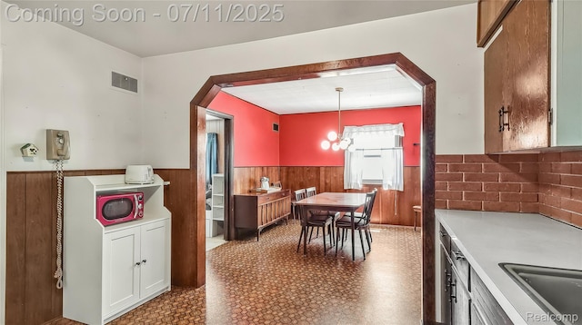 1845 Van Courtland Dr, Troy, MI 48083 - kitchen featuring a wainscoted wall, arched walkways, wood walls, light countertops, and tile patterned floors