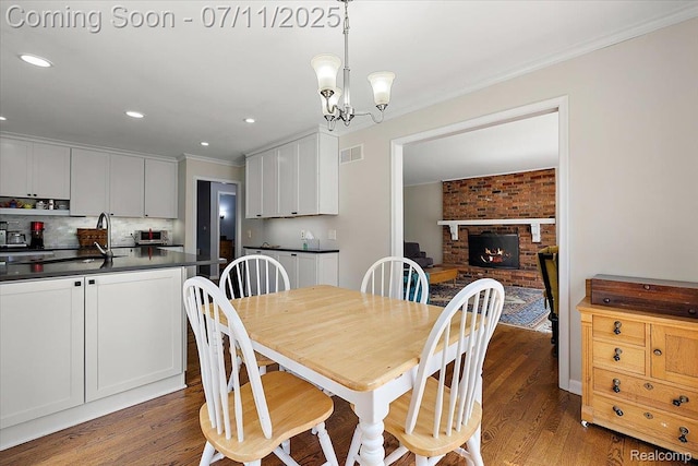 2403 Red Maple Ct, Troy, MI 48098 - dining room with crown molding, wood finished floors, a fireplace, recessed lighting, and a chandelier