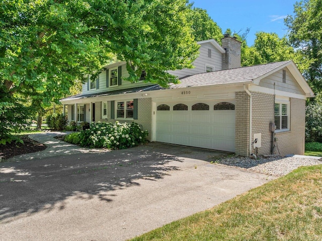 4550 Comanche Dr, Okemos, MI 48864 - view of front of property with brick siding, an attached garage, asphalt driveway, a chimney, and roof with shingles