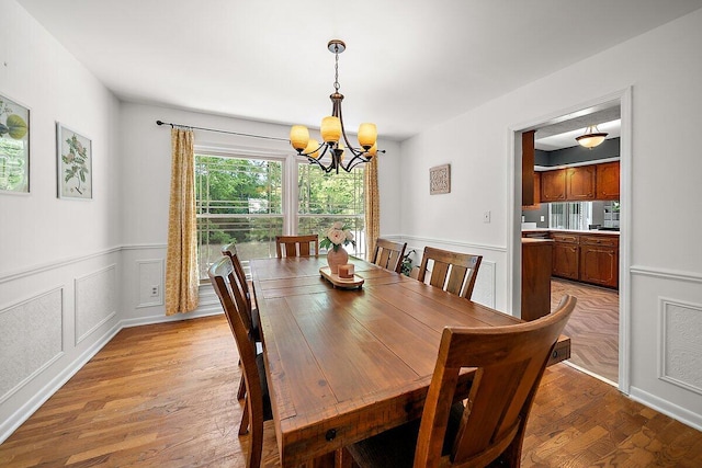 4550 Comanche Dr, Okemos, MI 48864 - dining space with a chandelier, a wainscoted wall, light wood finished floors, and a decorative wall
